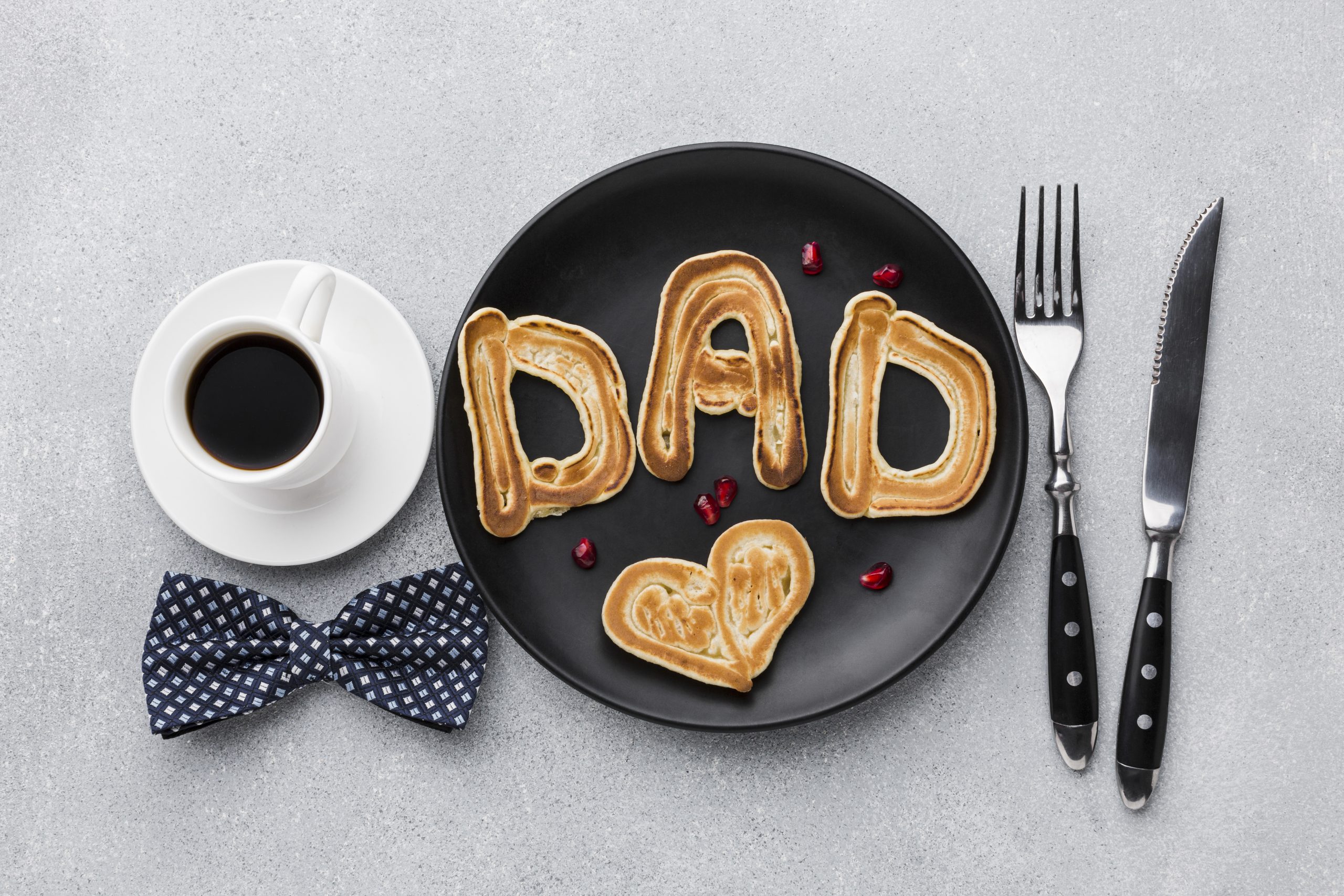 'Dad' on a plate with a coffee and bow tie one side and knife and fork the other