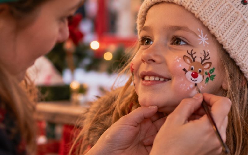 Close up of a woman face painting a child